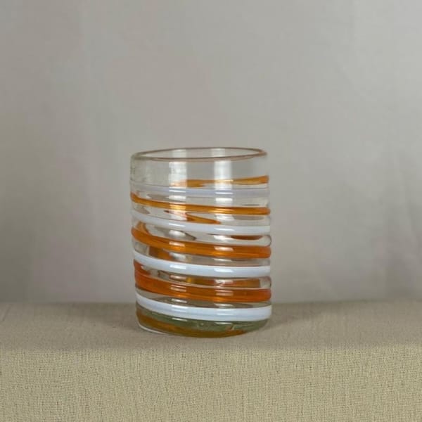 Vaso naranja y blanco sobre vidrio transparente